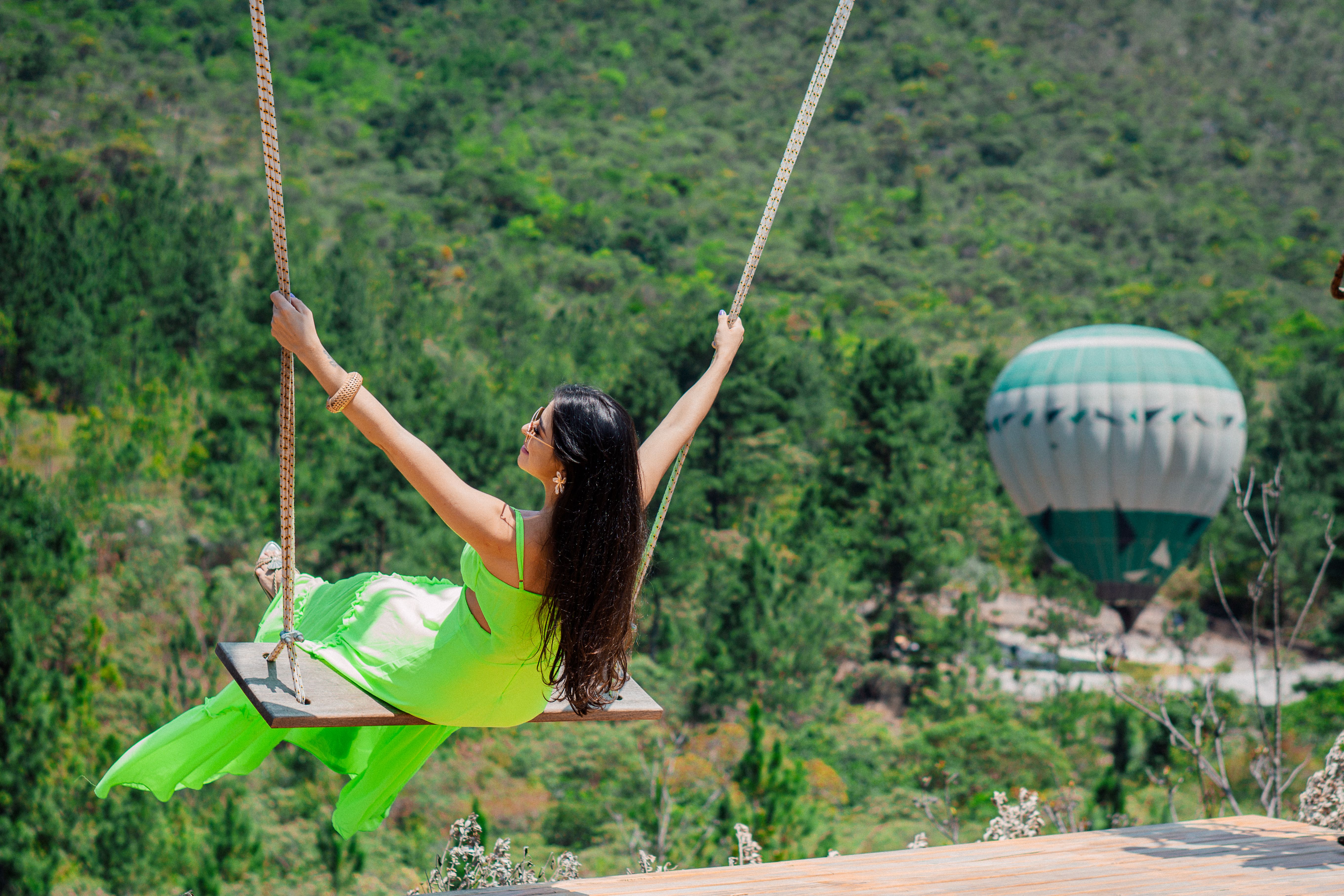 Person on a swing overlooking hot air balloons in the sky, scenic tours and experiences